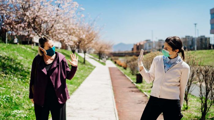 Friends wearing masks greeting each other outside