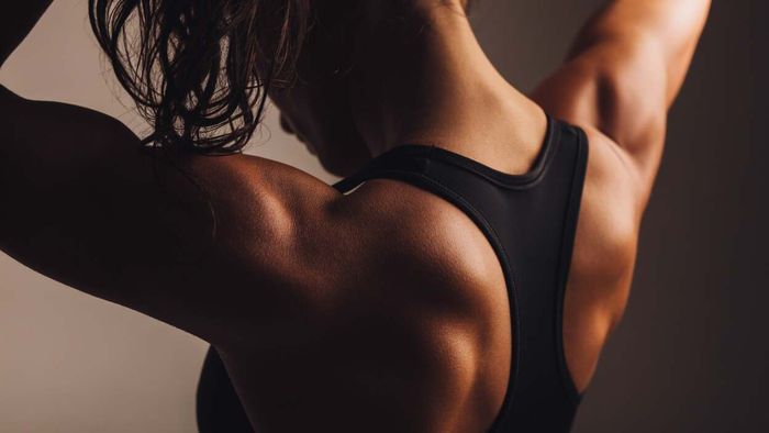 A fitness model proudly displaying her well-developed shoulder and back muscles.