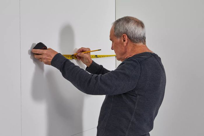 A person measuring a wall with the Crescent Lufkin Shockforce Dual-Sided Tape Measure