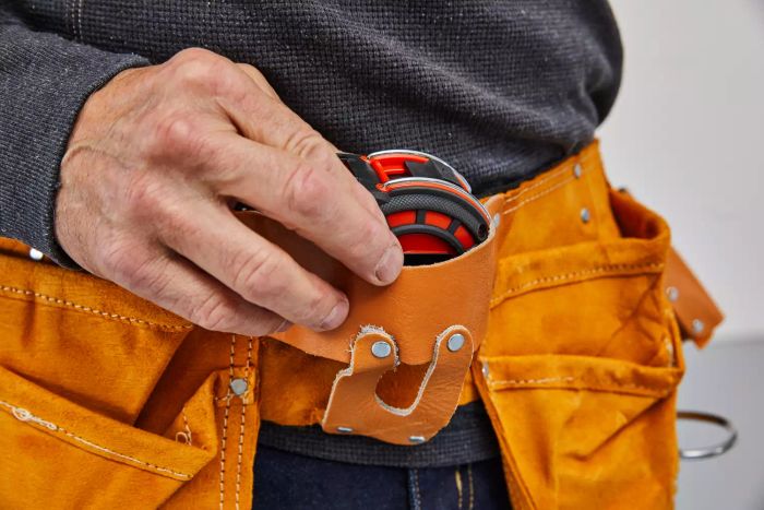 A hand removing the Crescent Lufkin Shockforce Dual-Sided Tape Measure from a hip belt