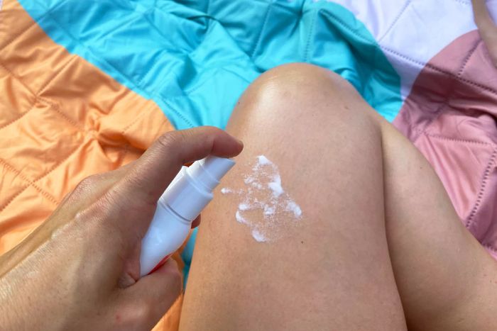 A person applying EarthKind Stay Away Mosquitoes Insect Repellent (20% Picaridin) to their leg