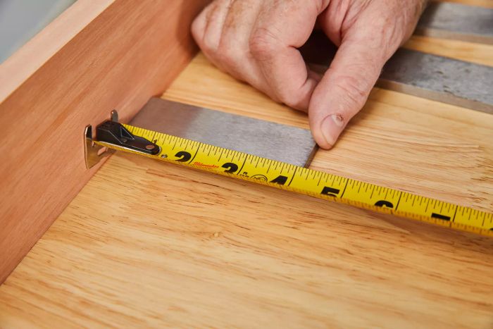A hand measuring a steel piece using the DeWalt Tough Series Tape Measure