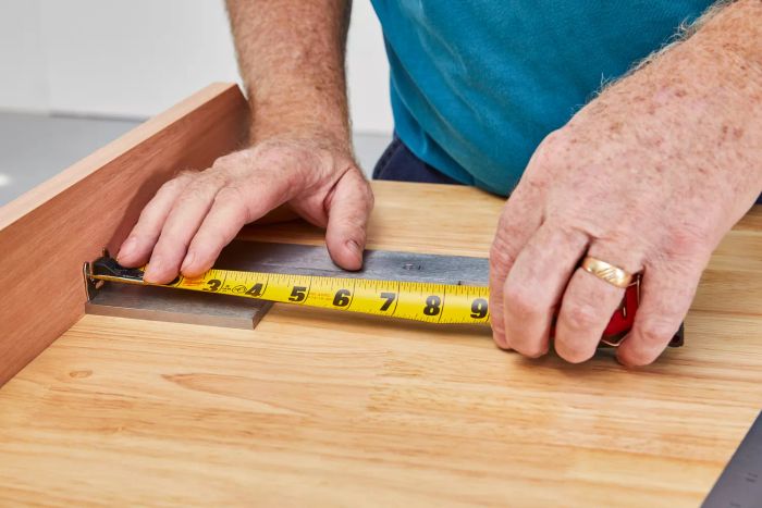 A person measuring steel with the Milwaukee Compact Tape Measure