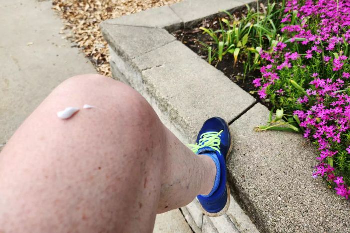 A person applying Sawyer Products 20% Picaridin Insect Repellent to their leg
