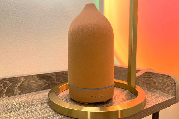 The Vitruvi Stone Ceramic Diffuser placed on a wooden side table