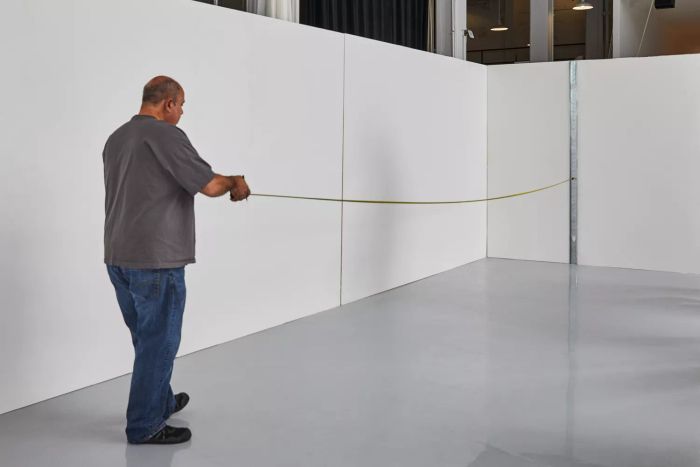 A person measuring a wall with the DeWalt Tough Series Tape Measure