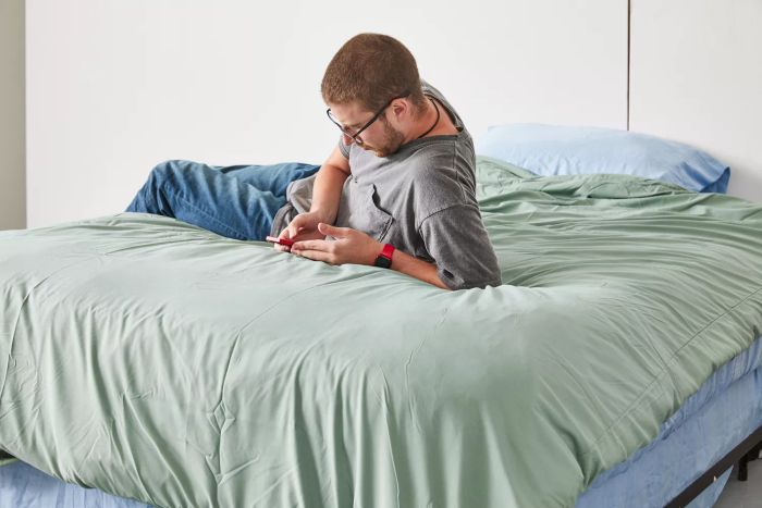 A person relaxing on the Cozy Earth Bamboo Comforter while using a phone on a bed