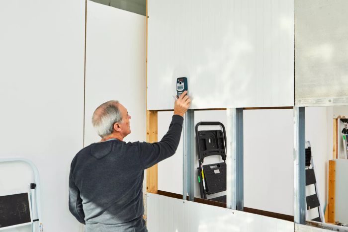 A person operating the Bosch GMS120 Digital Multi-Scanner to locate objects behind walls