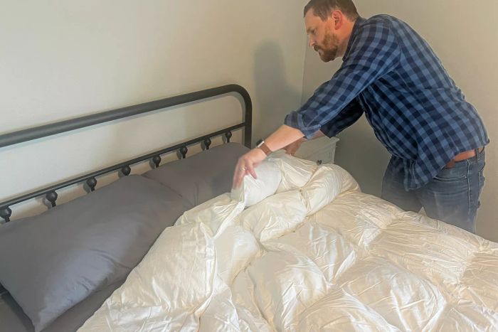 A person neatly arranging the Crane & Canopy Ultimate Luxe Down Alternative Comforter on a bed