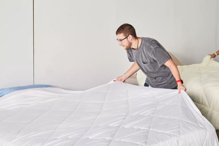 A person neatly arranging the Cozy Earth Bamboo Comforter on a bed