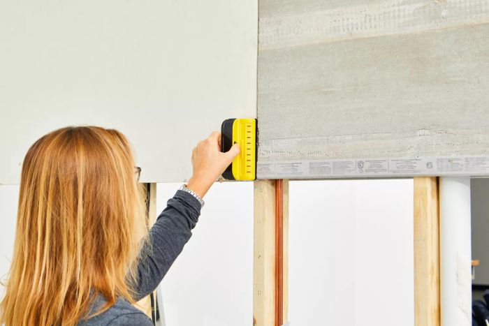 A person using the Franklin Sensors ProSensor M90 Professional Stud Finder against a wall