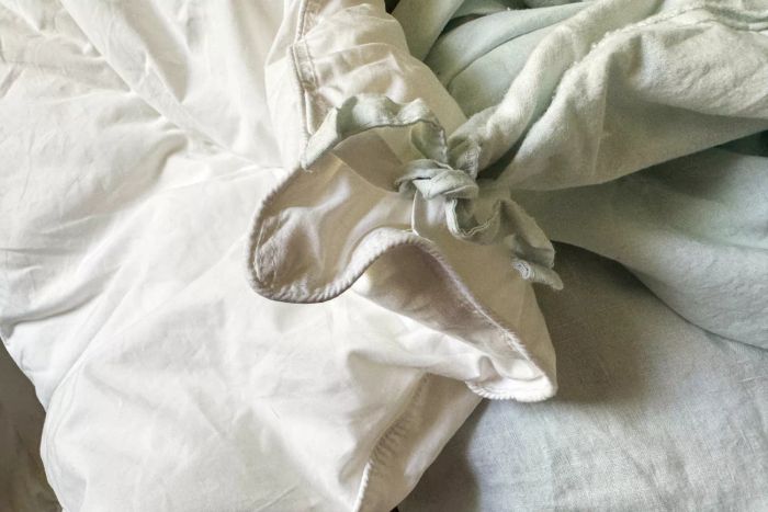 The Saatva Lightweight Down Alternative Comforter neatly spread out on a bed