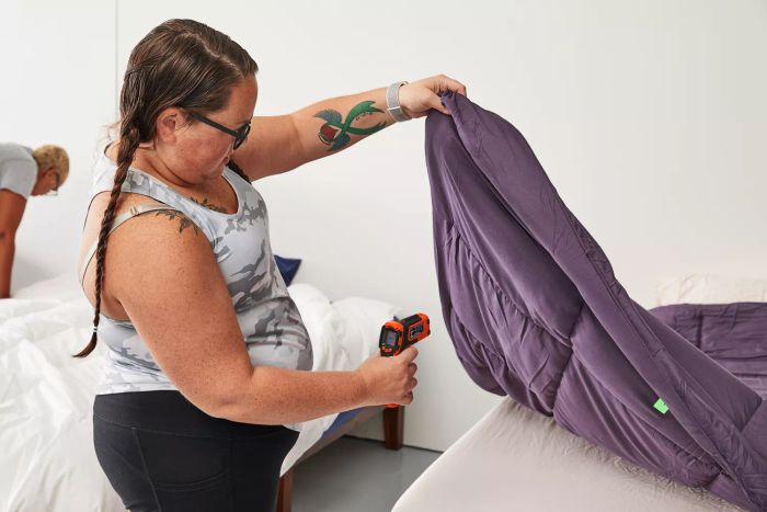 A tester using a thermometer to check the temperature of the Utopia Bedding All-Season Down Alternative Comforter