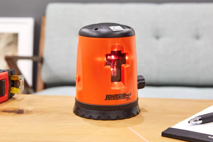 Johnson Level & Tool 40-0921 Self-Leveling Cross-Line Laser Level Kit shown on a table next to a pen and paper