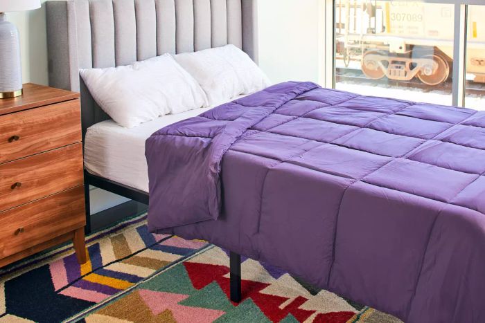 A bed adorned with pillows and a vibrant purple Utopia Bedding All-Season Down Alternative Comforter