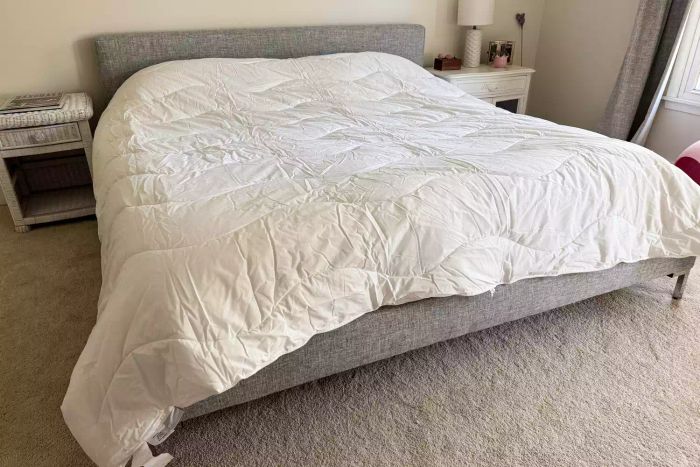 The Saatva Lightweight Down Alternative Comforter neatly laid out on a bed