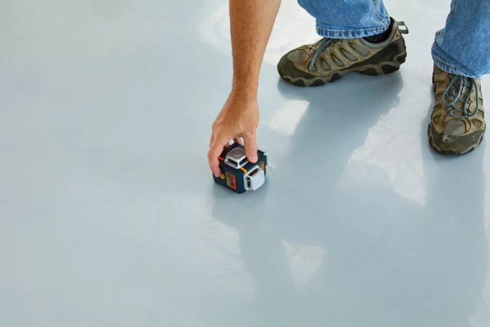 A person setting the Cigman 3x360 Degrees Green Laser Level on the floor