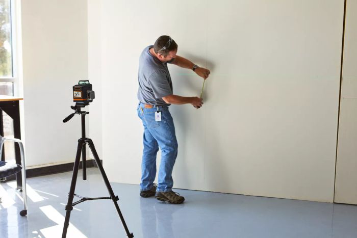 A person using the Cigman 3x360 Degrees Green Laser Level to check wall alignment accuracy