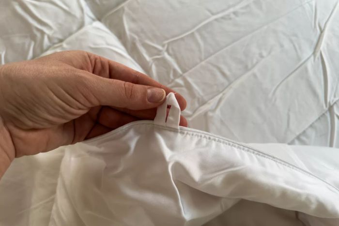 A person holding a duvet hook attached to the Sijo Clima Tech TempTune Comforter