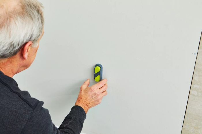 A person using the Calculated Industries 7310 StudMark Magnetic Stud Finder against a wall