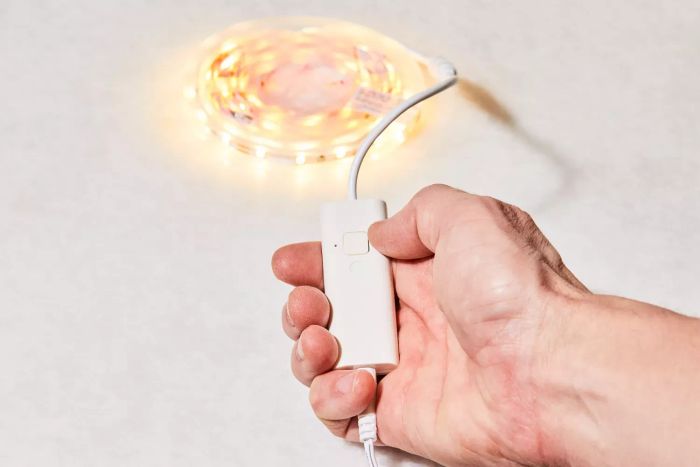 a person pressing the power button on the Wobane Under-Cabinet LED Lighting Kit