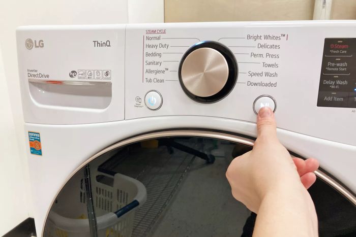 A person pressing the start button on the LG Electronics WM4000HWA Ultra Large Capacity Front Load Washer.