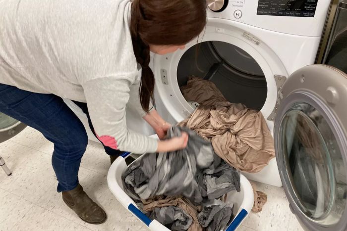 A person removing clothes from the LG Electronics WM4000HWA Ultra Large Capacity Front Load Washer.