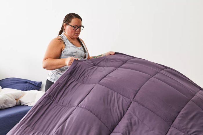 A person neatly arranging the Utopia Bedding All-Season Down Alternative Comforter on a bed