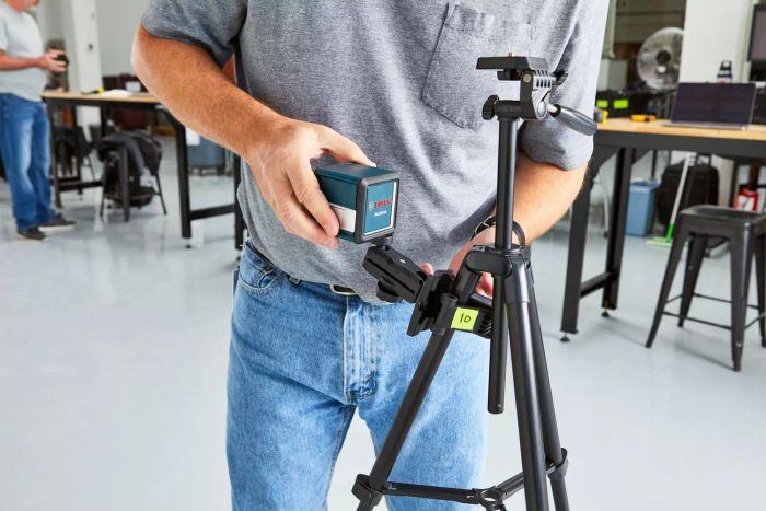 A person is examining the Bosch GLL25-10 Self-Leveling Laser Level