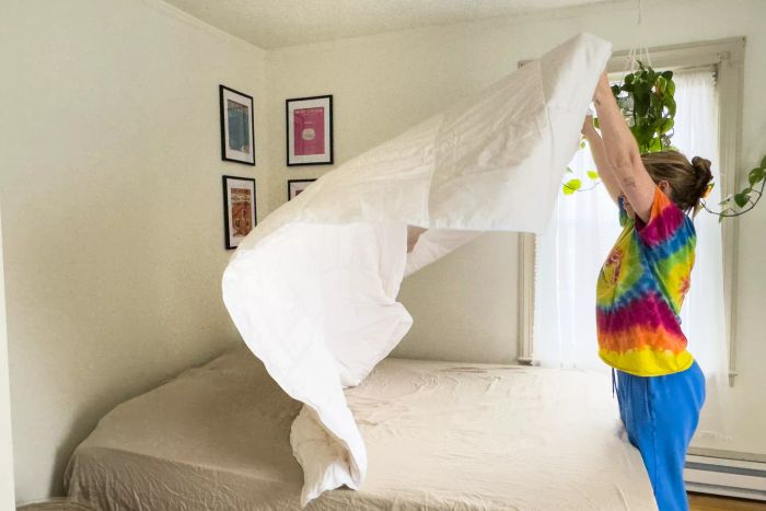 A person neatly arranging the Sijo Clima Tech TempTune Comforter on a bed