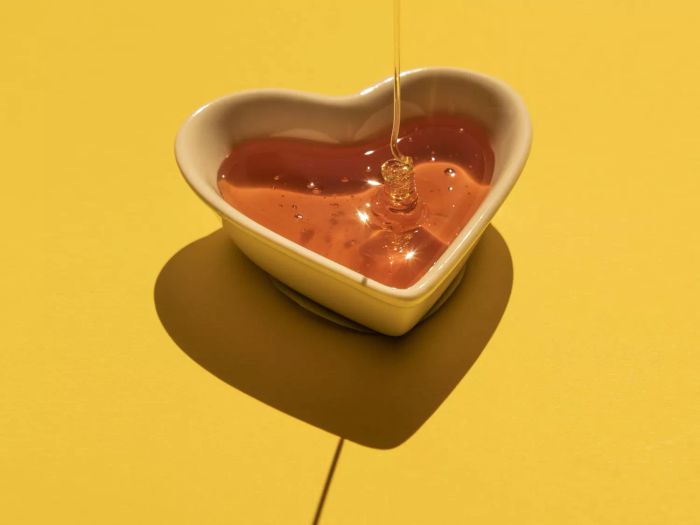 Honey On A Heart Shaped Bowl On Yellow Background