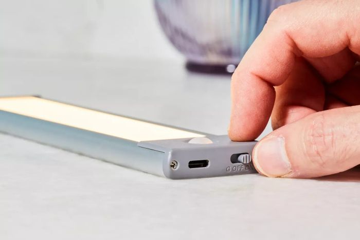 a person demonstrating the power options on the side of the Lepotec LED Motion Sensor Cabinet Light