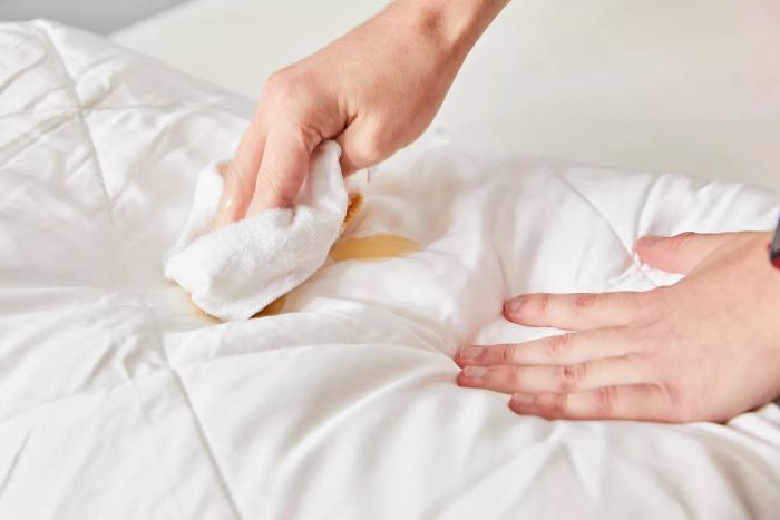 Hands gently wiping the Cozy Earth Bamboo Comforter with a washcloth