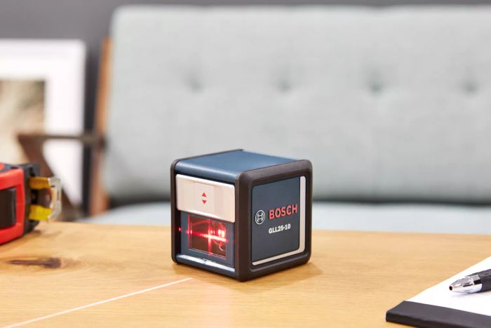 Bosch GLL25-10 Self-Leveling Laser Level placed on a wooden surface emitting a red light