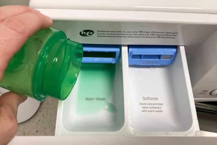 An individual adding laundry detergent to the LG Electronics WM4000HWA Ultra Large Capacity Front Load Washer.