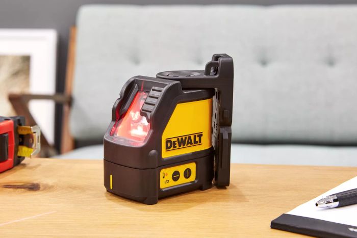 DEWALT DW088K Cross-Line Laser Level placed on a wooden surface beside a pen and notepad