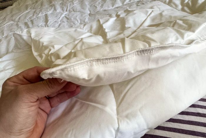 A person holding the Saatva Lightweight Down Alternative Comforter