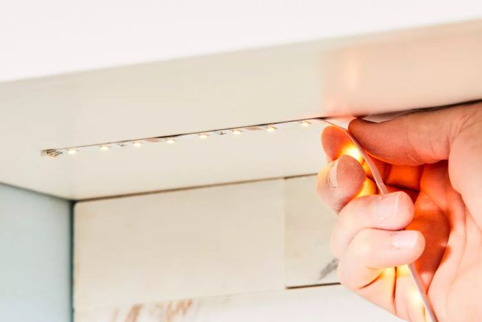 a person installing the Wobane Under-Cabinet LED Lighting Kit in a kitchen