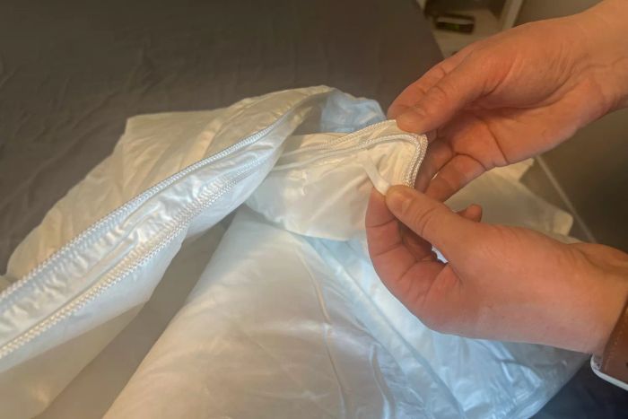 A person demonstrating the corner hooks on the Crane & Canopy Ultimate Luxe Down Alternative Comforter