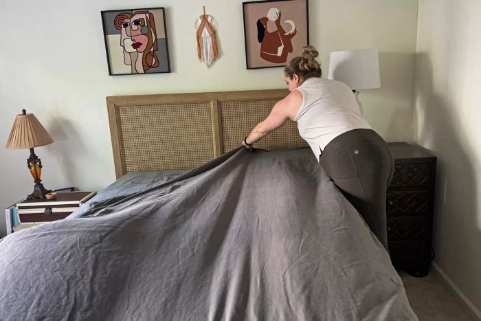 A person making a bed with the Sheets & Giggles Eucalyptus Lyocell Sheets Set