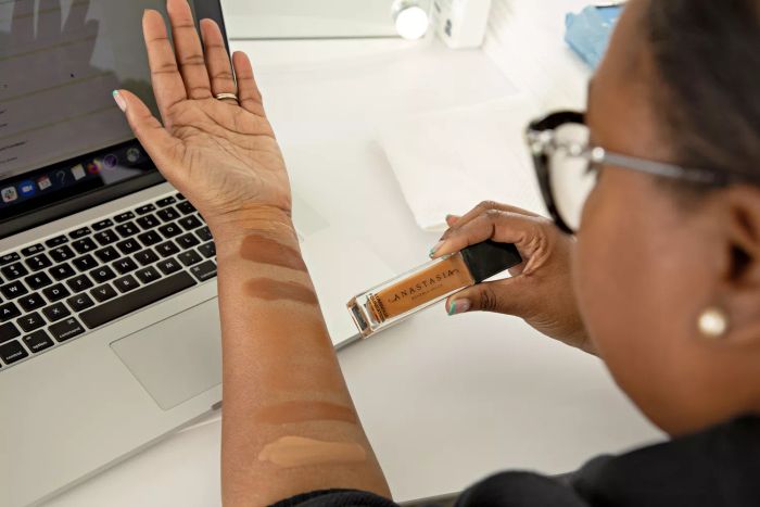 A woman swatching various foundation shades on her arm