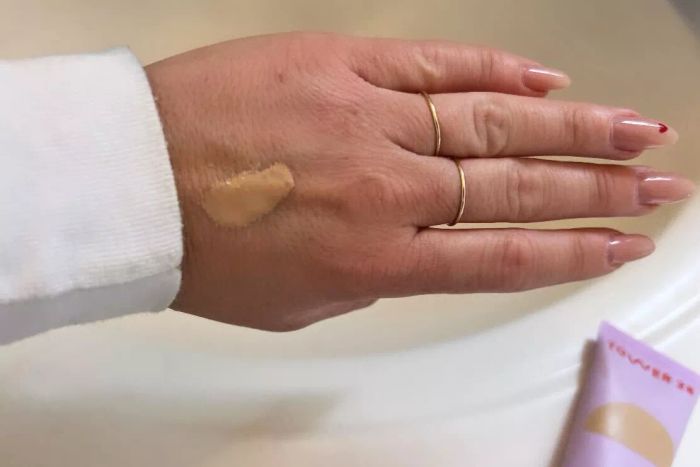 A person applies Tower 28 SunnyDays SPF 30 Tinted Sunscreen to the back of their hand