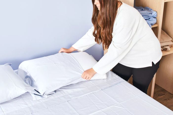 A person placing a pillowcase from the Molecule Sateen Performance Sheets onto a pillow