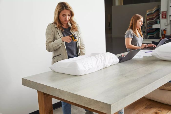 A person is measuring the Uttu Sandwich Pillow's temperature using a thermometer, placed on a table next to a laptop.