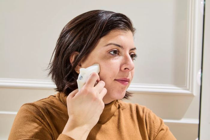 A person holds a device to their face after using Tower 28 SunnyDays SPF 30 Tinted Sunscreen