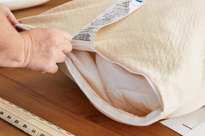 A person zips the cover onto the Birch by Helix Organic Pillow