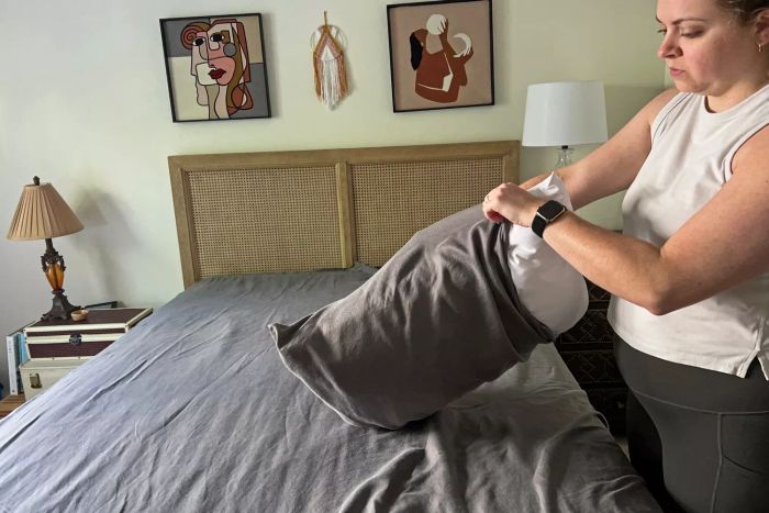A person placing a pillow into the Sheets & Giggles Eucalyptus Lyocell Sheets Set pillowcase