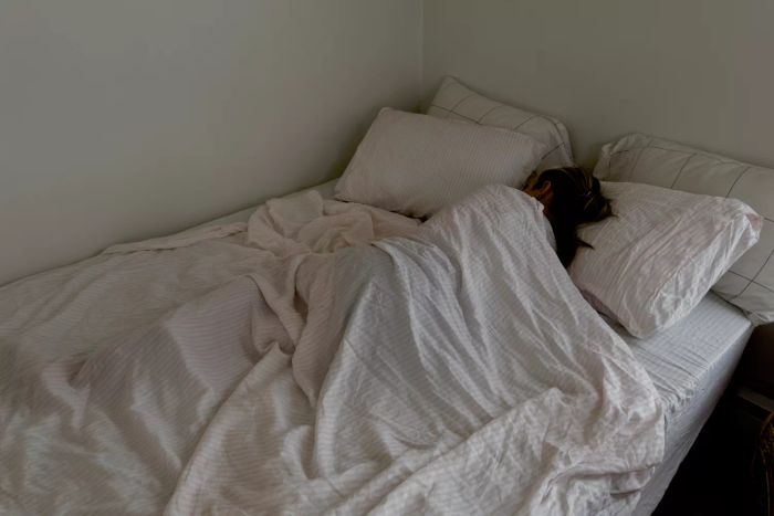 A person sleeping under the Buffy Breeze Sheet Set on a bed