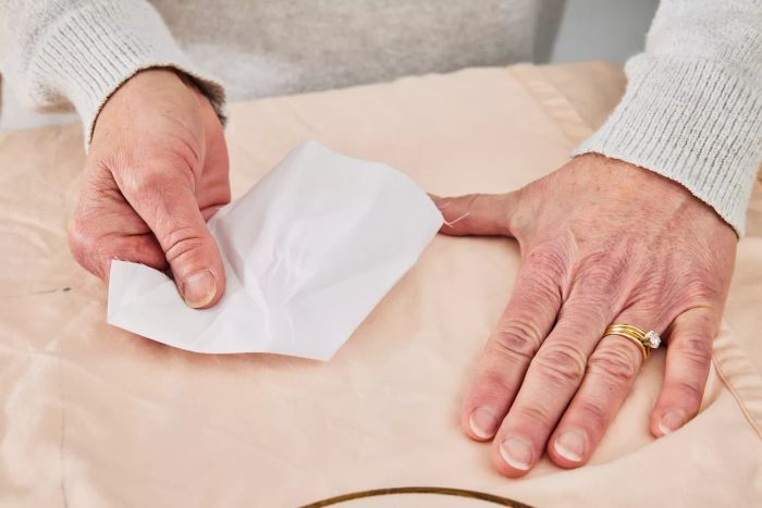Two hands placing a tissue on the Tempur-Pedic 400 Thread Count Cool Luxury Sheet Set
