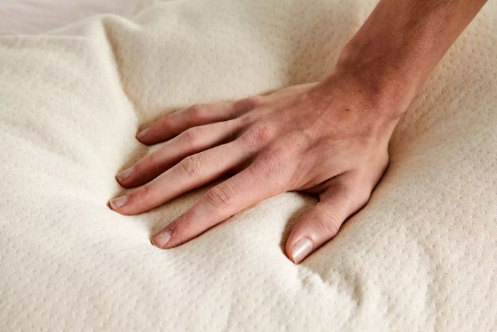 A person presses down on the Birch by Helix Organic Pillow